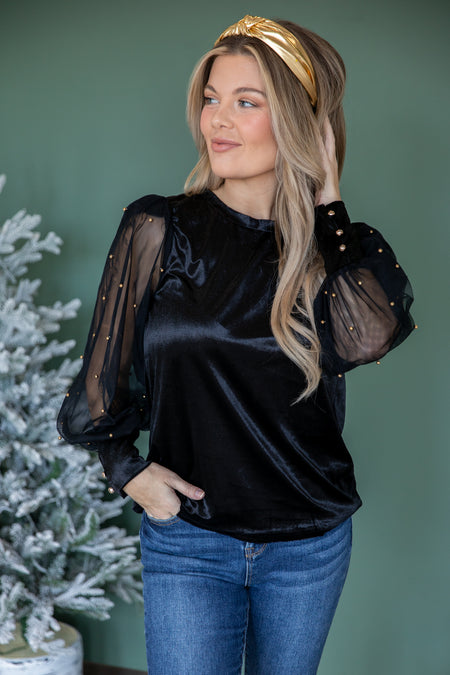 Woman in a velvet top with dark jeans, holiday party outfit